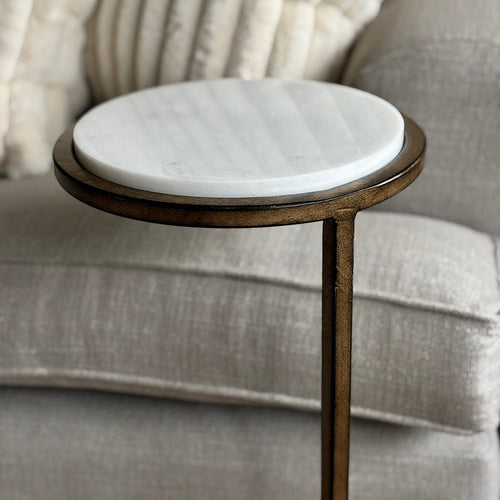 Small round side table with marble top next to a gray sofa