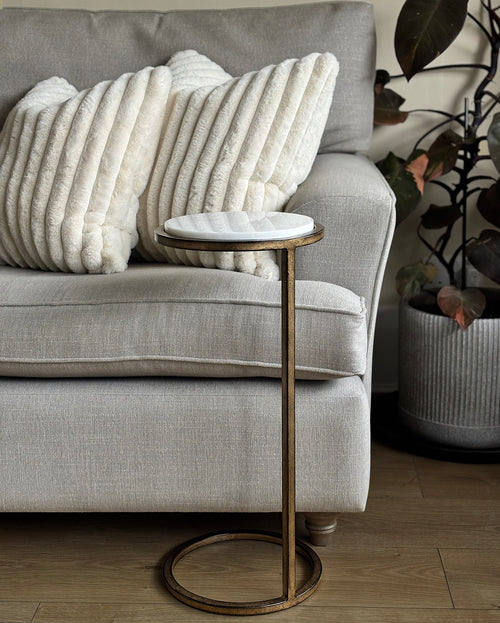 Gray sofa with textured white pillows and a small side table in a living room setting.
