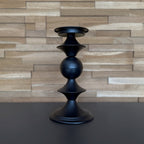 Black candle holder on a dark surface with a wooden wall background