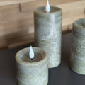 Three textured cylindrical candles with white wicks on a dark surface.