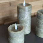 Three textured cylindrical candles with white wicks on a dark surface.