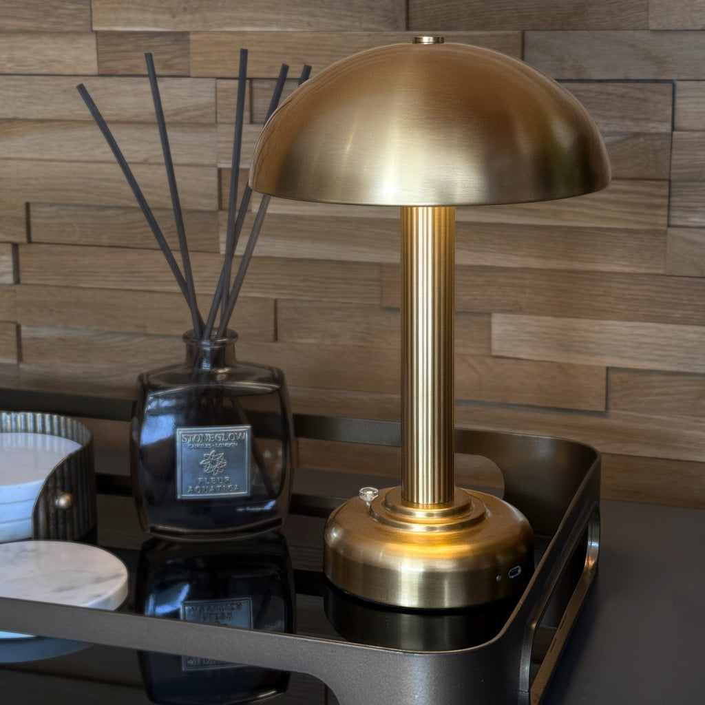 Brass table lamp on a reflective surface with a wooden wall background